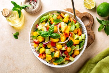 Kırmızı dolma biber, salatalık, kırmızı soğan, taze nane, fesleğen ve limon, zeytinyağı ve bal sosuyla yapılan mango salatasının en üst görüntüsü. Boşluğu kopyala.