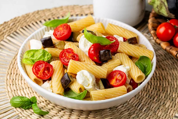 Kızarmış patlıcan, domates, mozzarella bufala peyniri ve fesleğen yapraklı İtalyan makarna rigatonisi. Yakın plan..