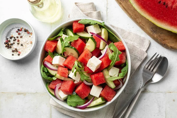 stock image Top view of Fresh summer salad with watermelon, arugula, feta, cucumber salad, healthy food eating. White table background.
