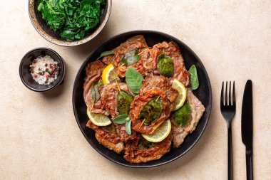 Top view of italian Roman dinner. Saltimbocca alla Romana, Italian dish. It consists of veal or beef, that has been cooked with prosciutto ham and sage and then cooked in wine. Sauteed Spinach. clipart