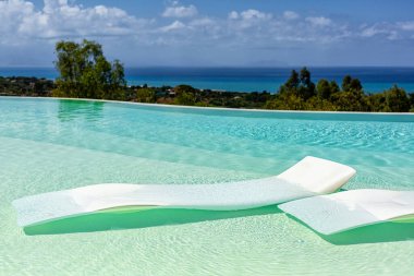 Yüzen plastik yataklı lüks bir yüzme havuzu güzel Akdeniz manzaralı bir tatil köyünde dinlenme yeri. İtalya, Sicilya.