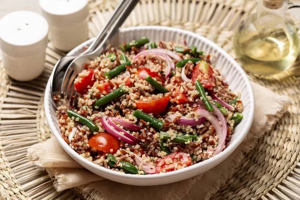 Cold quinoa salad with green beans, tomato, marinated red onion and red rice. Vegetarian healthy meal.