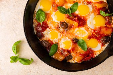 Kızarmış bıldırcın yumurtalı Shakshouka, sebze, domates, dolmalık biber, zeytin, soğan, fesleğen yaprağı. Yakın plan..