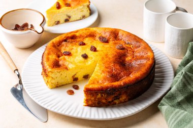 Ev yapımı süzme peynirli güveç ve kuru üzüm. Süt ürünleri, yumurta, irmik unu ve vanilyalı peynirli kek. Bej tablo.