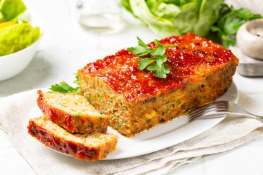 Köfte ya da terrine, tavuk ve hindi eti, havuç, pırasa ve ketçapla kaplanmış yeşil bezelye. Fırında kızarmış tavuk eti. Beyaz tablo yüzeyi.