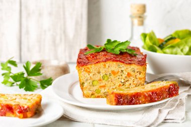 Köfte ya da terrine, tavuk ve hindi eti, havuç, pırasa ve ketçapla kaplanmış yeşil bezelye. Fırında kızarmış tavuk eti. Beyaz tablo yüzeyi.