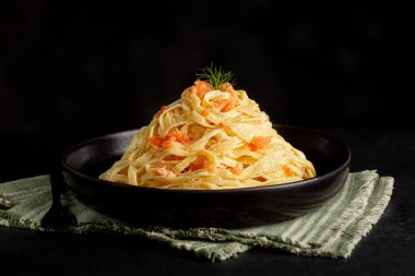 Bir tabak füme somon alfredo makarna. Tagliatelle ya da krema soslu fettuccine ile yapılır. Siyah arkaplan.