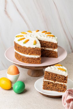 Ev yapımı havuçlu kek cevizli, krem peynirli. Renkli Paskalya yumurtaları. Tatlı tatlı. Şenlik arka planı. Dikey resim.