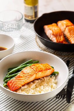 Ballı tabak, portakal suyu sarımsaklı somon balığı, uzun pirinç ve keten işlemeli yeşil fasulye. Demir döküm. Dikey resim.