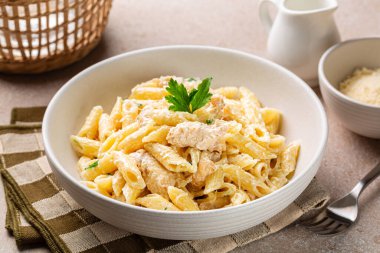 Tavuk Alfredo Penne, kremalı makarna beyaz tabakta parmesan peyniri..