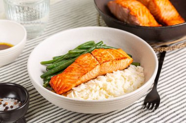 Tatlım, portakal suyu sarımsaklı ızgara somon balığı uzun pirinç ve yeşil fasulye ile beyaz tabakta..