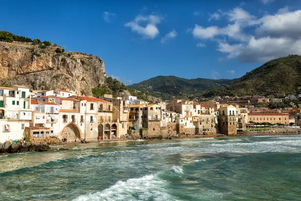 Zeytin ağaçları Sicilya 'nın kostal bir bölgesinde yetişir, İtalya' da tarım. Arka planda Cefalu kasabasının güzel panoramik manzarası, Palermo Metropolitan Şehri. Ağustos 2023.