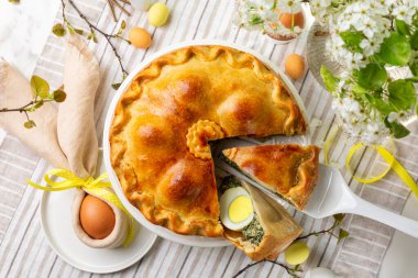 Paskalya masasının hemen üstünde renkli yumurtalar, çiçekler, Savory Pasqualina, ıspanak, gümüş pancar, pırasa, peynir ve kaynamış yumurtalardan yapılmış Torta Pasqualina var. Ev yapımı yemek..