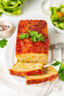 Köfte ya da terrine, tavuk ve hindi eti, havuç, pırasa ve ketçapla kaplanmış yeşil bezelye. Fırında kızarmış tavuk eti. Beyaz tablo yüzeyi, dikey resim.