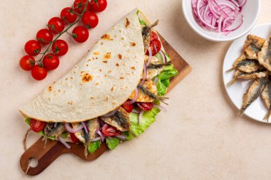 Geleneksel İtalyan dürümü ya da açık sandviç manzarası. Piadina romagnola con sarde fritte. Kızarmış sardalyalı yağlı ekmek balık, domates, kırmızı soğan ve marul. Sokak yemeği..