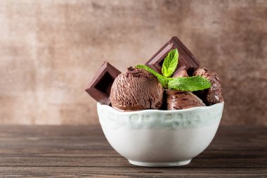 Çikolatalı dondurma ve çikolatalı kase, taze nane. Kahverengi arkaplan.