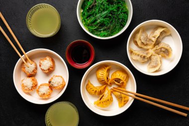 Çin yemeğinin farklı hamur tatlısı manzarası. Ravioli, Shao Mai, Goma Wakame veya yosun salatası. İçkiler.. 
