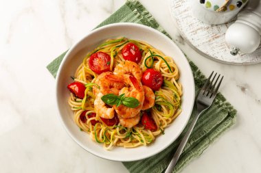 Bir tabak İtalyan makarnası. karides, domates ve kabak ya da kabak, spagetti. Üst manzara, beyaz mermer masa..