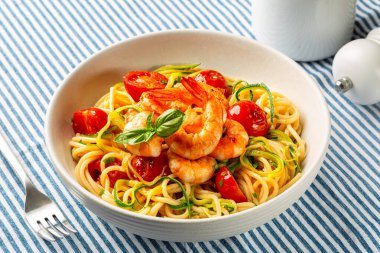 İtalyan makarnası yakın çekim. Karides, domates ve kabak, ya da kabak, tekstil işindeki spagetti tabağı..