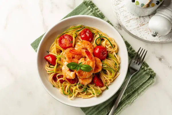 Bir tabak İtalyan makarnası. karides, domates ve kabak ya da kabak, spagetti. Üst manzara, beyaz mermer masa..