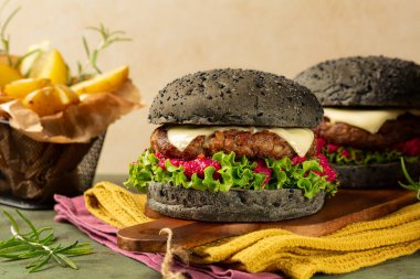 Kömürle yapılmış, hamburgerli, kıymalı et, peynir, marul ve pancar humusundan oluşan bir köfte. Fırında patates. Bayram yemeği konsepti. Bej arkaplan.