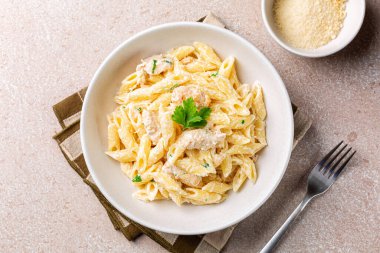Tavuk Alfredo Penne, kremalı makarna beyaz tabakta parmesan peyniri. Tam üstte.