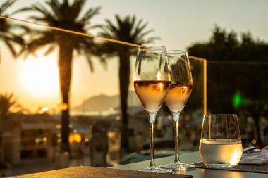 Hırvatistan şehir plajında romantik bir günbatımı yemeği. İki kişilik şarap bardaklı masa ya da deniz manzaralı bir restoranda içecek.. 