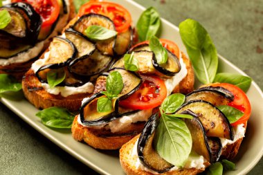 Akdeniz açık sandviçi ya da kızarmış ekmek, robiolla peyniri, domates ve fesleğen yapraklı kızarmış patlıcan.. 