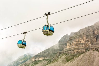 Adamello Brenta, ITALY - August 22, 2024. Cable car in Mountain top of the national park in a foggy, cloudy day, Italy.  The Dolomites mountains near Madonna di Campiglio village.  clipart