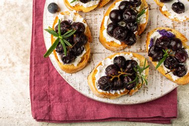 Kırmızı üzümlü beyaz tahta ve biberiyeli keçi ricotta peynirli crostini.. 