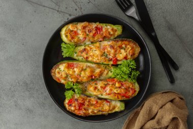 Fırında pişirilmiş kabak, tavuk eti, güzel biber, domates ve peynir ile doldurulmuş koyu yeşil masa yüzeyinde. Doğrudan Üstte.