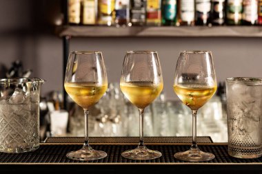 Bir barda, barda ya da restoranda üç bardak soğuk beyaz şarap. Servis edilmeye hazır..