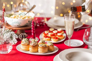 Şişeden bardağa akan köpüklü şarap. Ev yapımı yemekler, farklı mezeler, tavuk salatalı vol-au-vent, havyarlı kanepe ve yumurta, mumlar ve dekorasyon servis edildi. Akşam yemeği partisinin yaşam tarzı foto.