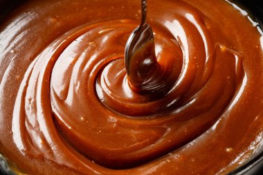 Karamel sosu pişirmek, kaşıkla karıştırmak, yakın plan, yemek arkaplanı..