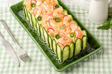 Swedish sandwich cake Smorgastarta, composed of layers of bread bound with filling egg and mayonnaise, salmon fish, avocado, prawns, decorated with cucumbers and radish.. High angel view. clipart