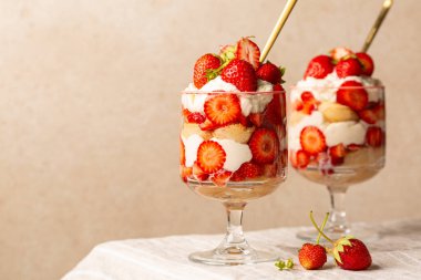 Çilekli tiramisu ya da bardaktaki ıvır zıvır. Işık masasında İtalyan tatlısı ve bej arka plan. Boşluğu kopyala.