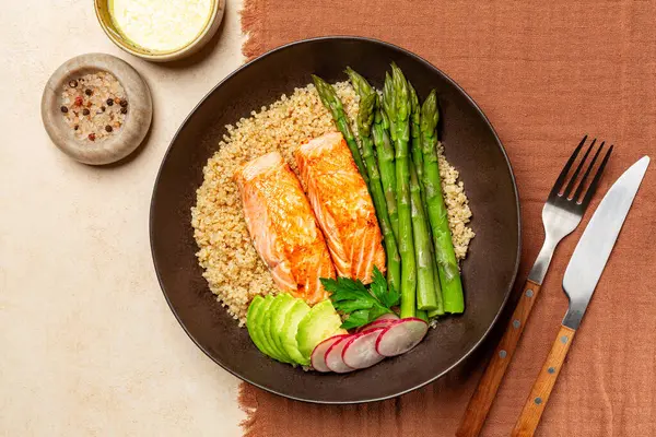 Somon, kinoa ve kuşkonmazlı tabağın üst görüntüsü, moka rengi tekstil arka plan, sos.