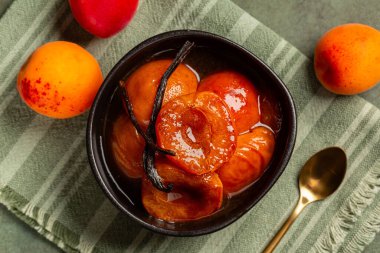 Siyah bir kasede şarap ve vanilyalı karamelize kayısılar. Taze meyve. Derince yukarıda.. 