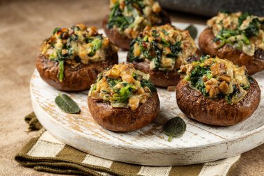 Close up of Baked Cremini Mushrooms stuffed with roasted mushrooms legs, with onion, spinach, bread crumbs and goat cheese.
