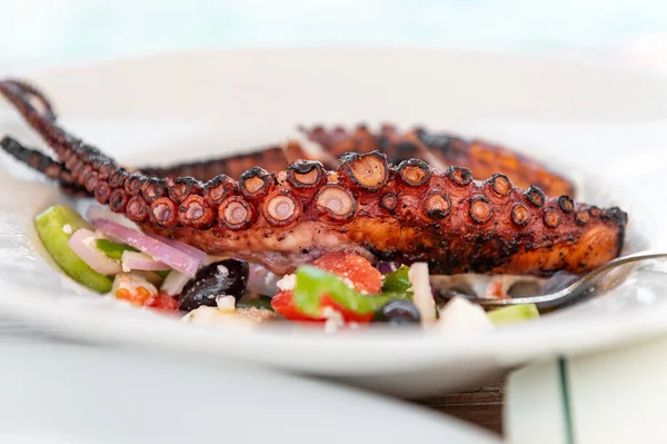 stock image Traditional Greek Salad served with Fried Octopus in tavern, traditional greece food. Tomatoes, cucumber, onions, olives, peppers, cappers and olive oil