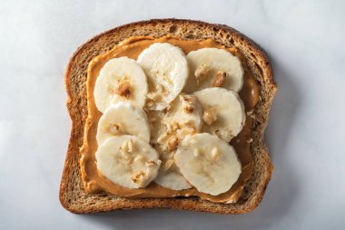 Fıstık ezmeli, muzlu ve ezilmiş cevizli kepekli ekmeğin açık sandviçi.