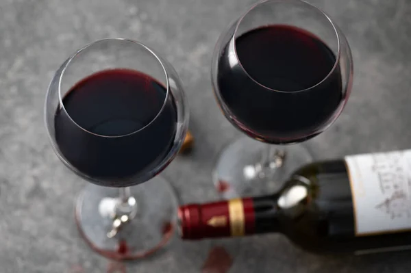 Glasses of red wine with empty bottle lying nearby and spilled drops of wine, shot from above