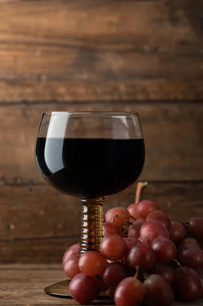 近くに赤ブドウの赤ワインのグラス 暗い素朴な背景 — ストック写真