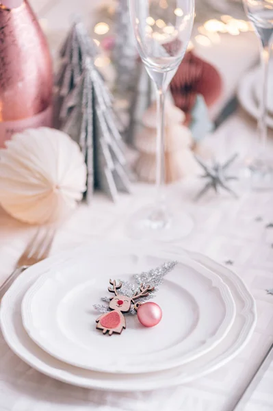 クリスマスツリーを背景に白とピンクの色のクリスマステーブル設定 空のプレートとグラスはお祝いのディナーやパーティーの準備ができて — ストック写真