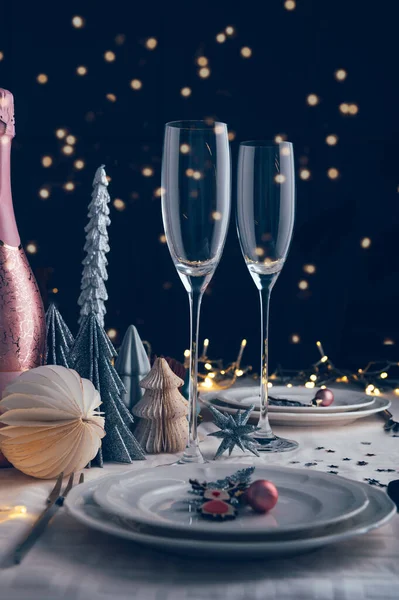 クリスマスツリーを背景に白とピンクの色のクリスマステーブル設定 空のプレートとグラスはお祝いのディナーやパーティーの準備ができて — ストック写真
