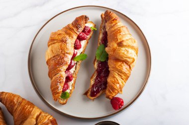 Kahvaltıda kruvasan, ricotta veya krem peynir, taze ahududu veya reçel ve nane yapraklı lezzetli sandviçler.