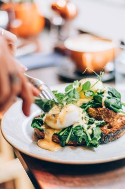 Healthy balanced breakfast with poached eggs, spinach and hollandaise sauce on toasted sourdough bread
