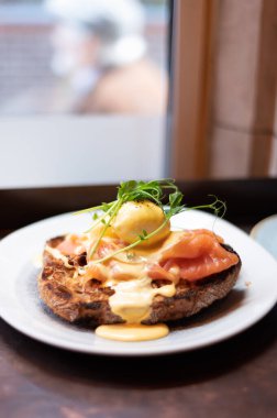 Healthy balanced breakfast with poached eggs, smoked salmon and hollandaise sauce on toasted sourdough bread