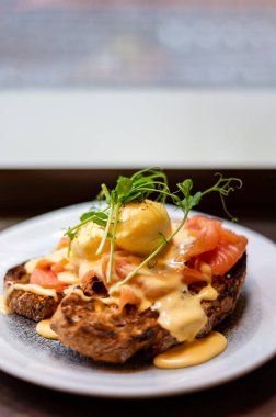 Healthy balanced breakfast with poached eggs, smoked salmon and hollandaise sauce on toasted sourdough bread