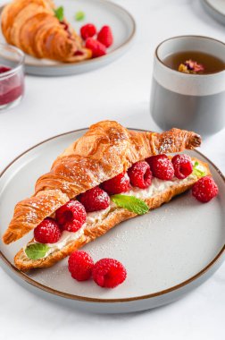 Kahvaltıda kruvasan, ricotta veya krem peynirli, taze ahududu ve nane yapraklı lezzetli sandviçler.